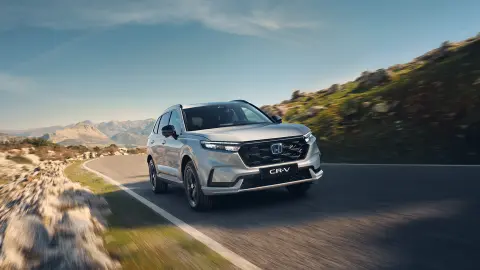 CR-V plugin hybrid white car driving on the road in a mountain location.
