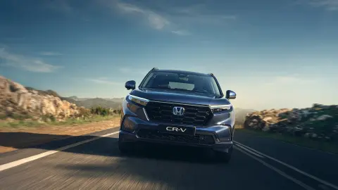 Front view of CR-V Hybrid car driving on the road in a mountain location.
