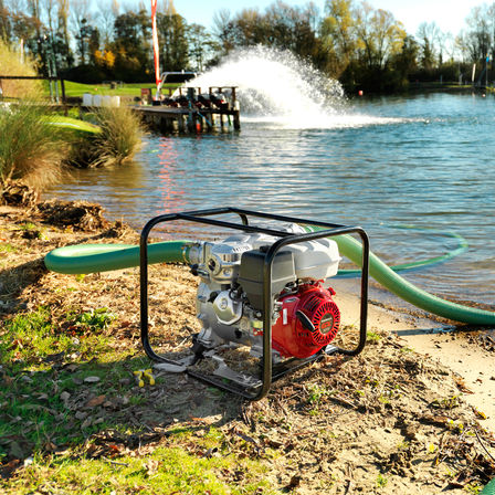 Dirty water trash pump with black frame in use near lake