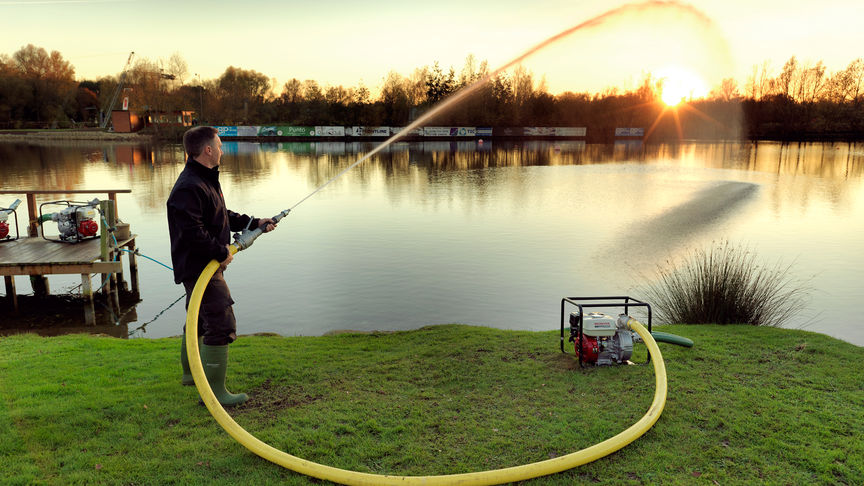 High pressure water pump being used by man in a lake setting