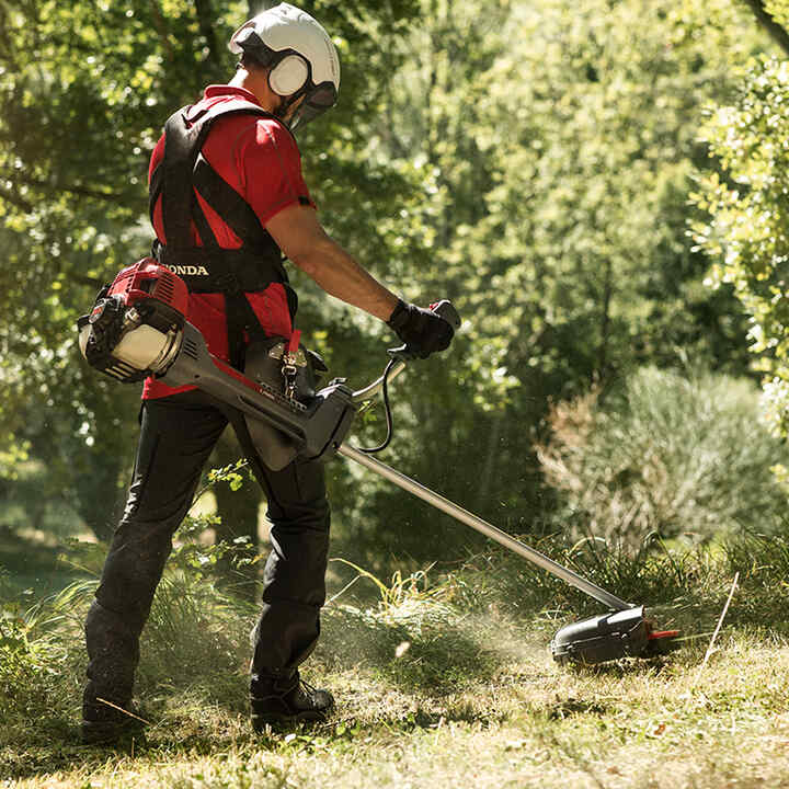 Man using brushcutter with a white helmet