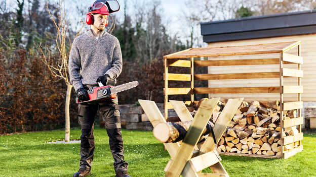 Man in garden location using a Cordless Chainsaw.