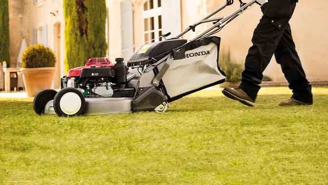 Lady with Honda IZY lawnmower cutting grass in garden location