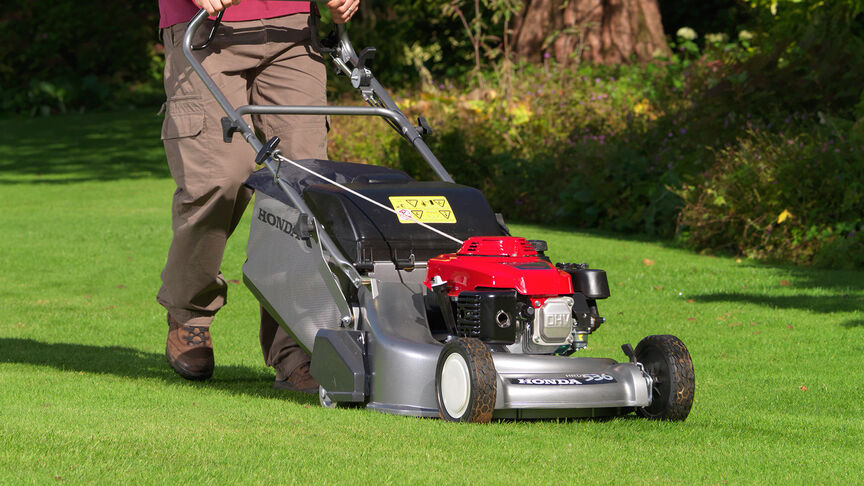 Man in garden location mowing grass with a Honda HRD lawnmower.
