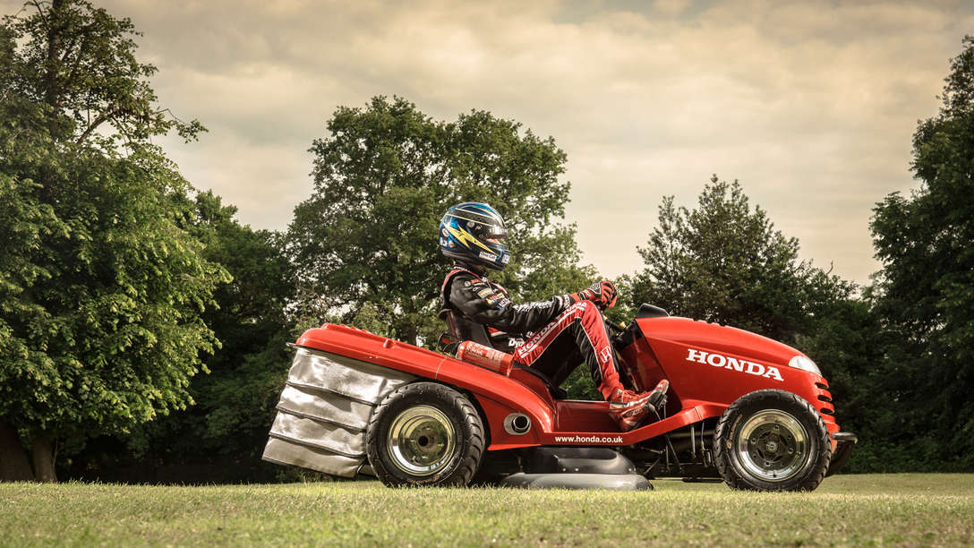 Premium lawn tractor, side view, being used by model, garden location.