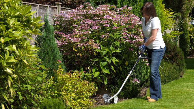 Honda Versatool with edger attachment, being used by model, garden location.
