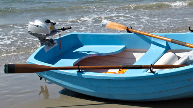 side view of boat parked on the beach fitted with a honda 2-3 horsepower outboard engine