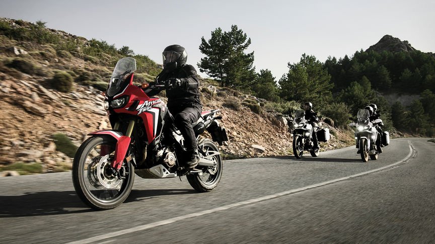 Three Africa Twin bikes coming around a bend in the road