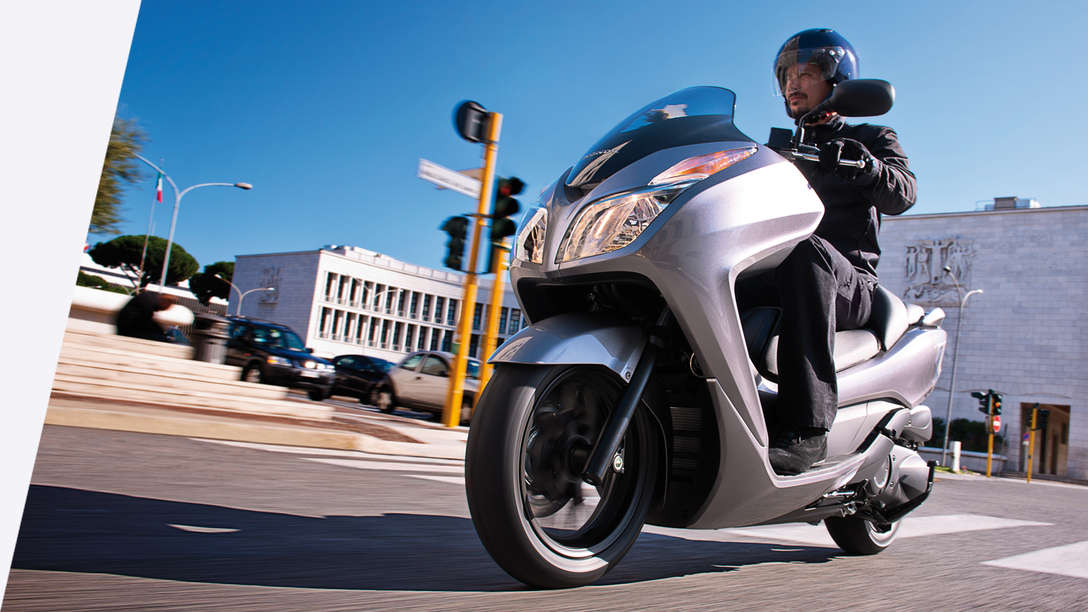 Honda Forza 300 motorbike front-threequarter view with rider. left-facing (Road location).