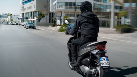 Rear view of Vision scooter, 3-quarter view, with rider on urban road location.