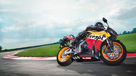 Honda CBR600RR Repsol-liveried motorbike front-threequarter view with rider, right-facing (Race track location).