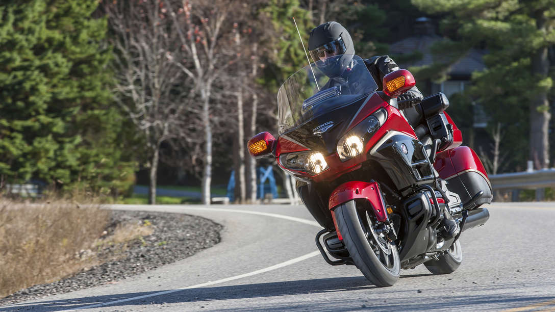 Front-facing Gold Wing,Road location with rider and pillion, right facing.