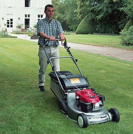 Front three-quarter lawnmower, being used by model, garden location.