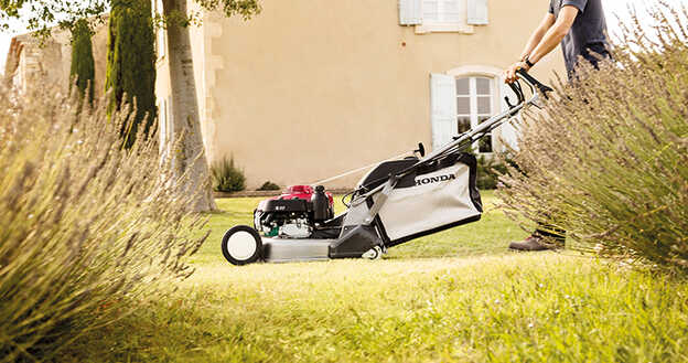 Honda HRD lawnmower side view in garden location with height adjustment points.