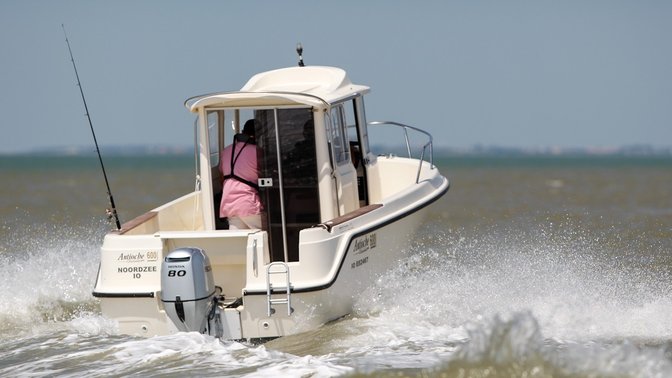 rear angled view of a person steering a boat powered by a 80 horsepower honda outboard engine