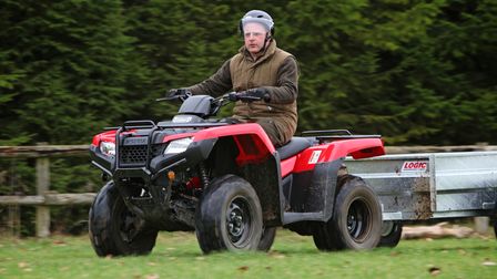 Honda Fourtrax 420 being ridden in a field towing a trailer