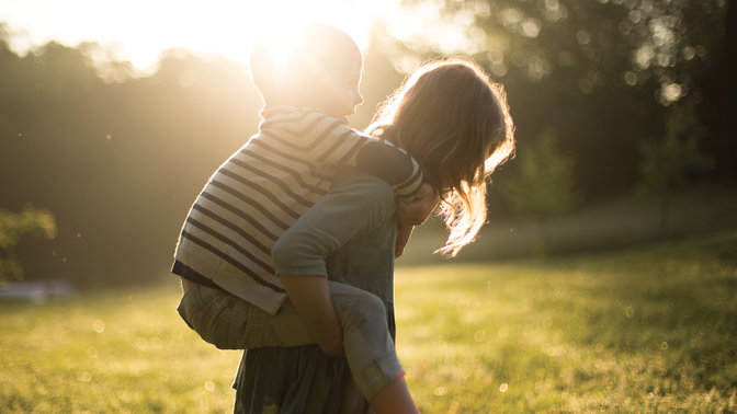 A girl carrying her brother