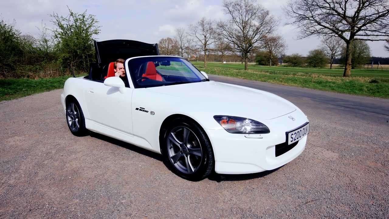 White S2000 parked on a road next to fields.