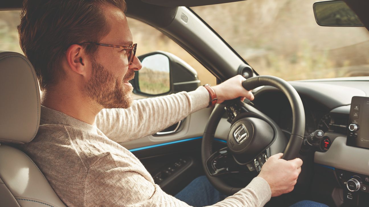 man with glasses driving a Honda car
