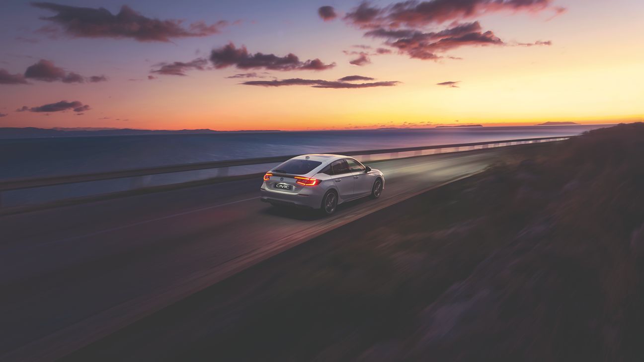 a white Honda Civic driving at sunset