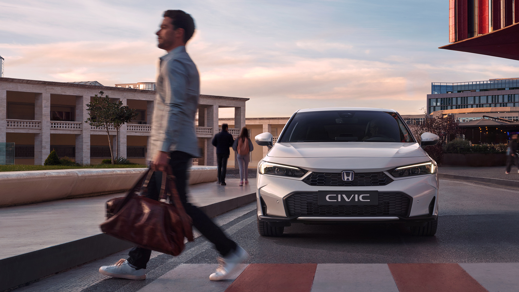 Honda Civic Hybrid approaching a man in front of a pedestrian crossing.