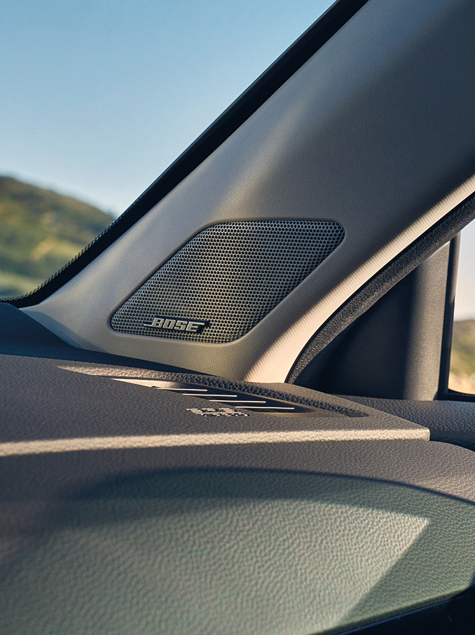  A close-up shot of a Bose speaker integrated into the interior A-pillar of a car, positioned near the dashboard and windshield.
