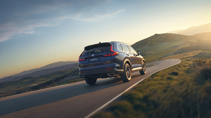 Rear side view of blue CR-V Hybrid SUV car in mountain location.