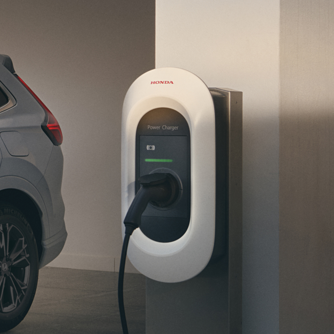 Front three-quarter facing Honda CR-V Hybrid plugged in to charge.