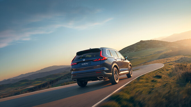 Rear side view of blue CR-V Hybrid SUV car in mountain location.