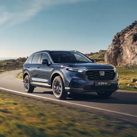 CR-V Hybrid SUV car driving on the road in a mountain location.