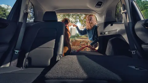 CR-V Hybrid SUVrear seat reclined with female and dog at the open boot. 