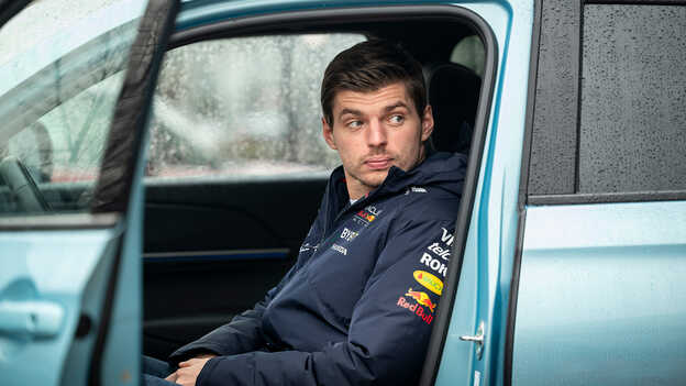 Max Verstappen sitting inside a blue Honda eny1 car parked.