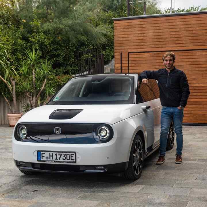 Pierre Gasly standing beside Honda e