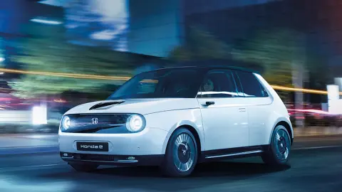 Honda e driving in city location.