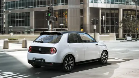 Side view of Honda e driving in a city location.