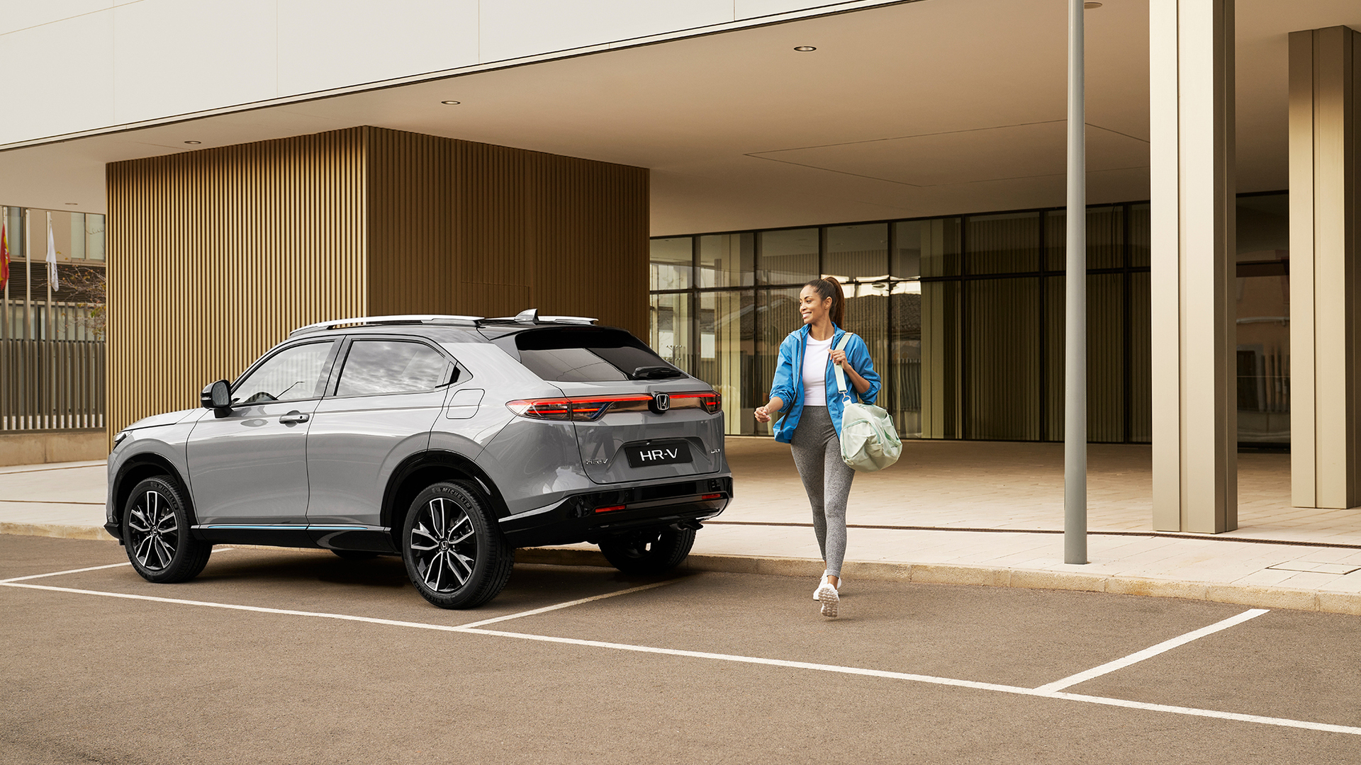 Woman walking allongside parked HR-V. 