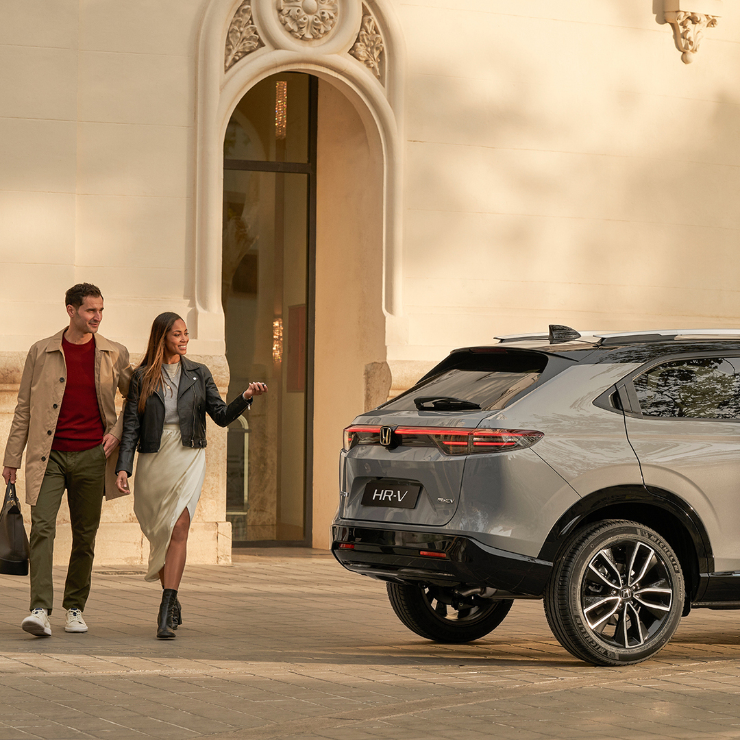 Couple walking next to  HR-V parked outside of building location. 