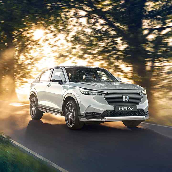 Front three-quarter facing Honda HR-V Hybrid driving through the country.