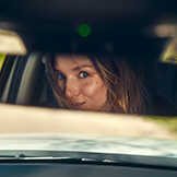 Woman smiling in rear view mirror