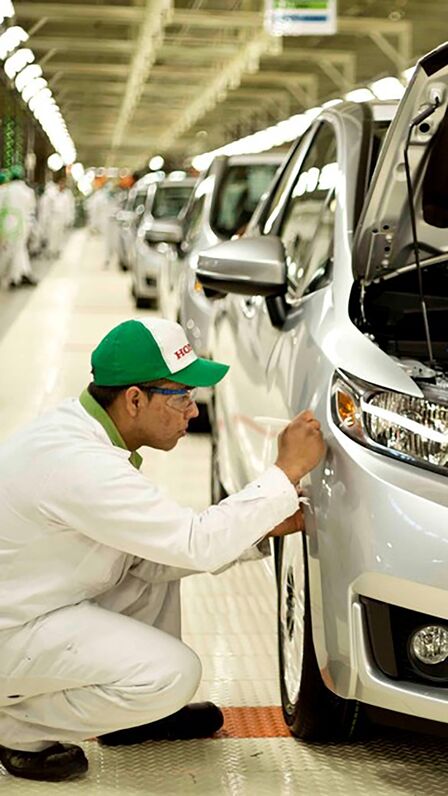 Honda technician working on a car in the factory.