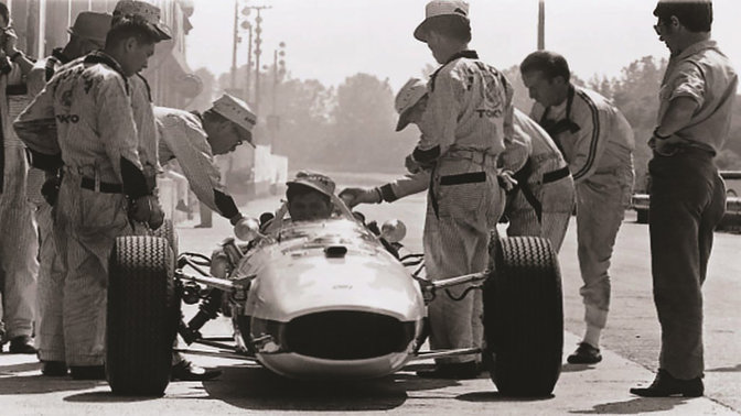 Front facing Honda Formula One car from the sixties with race driver and engineers.