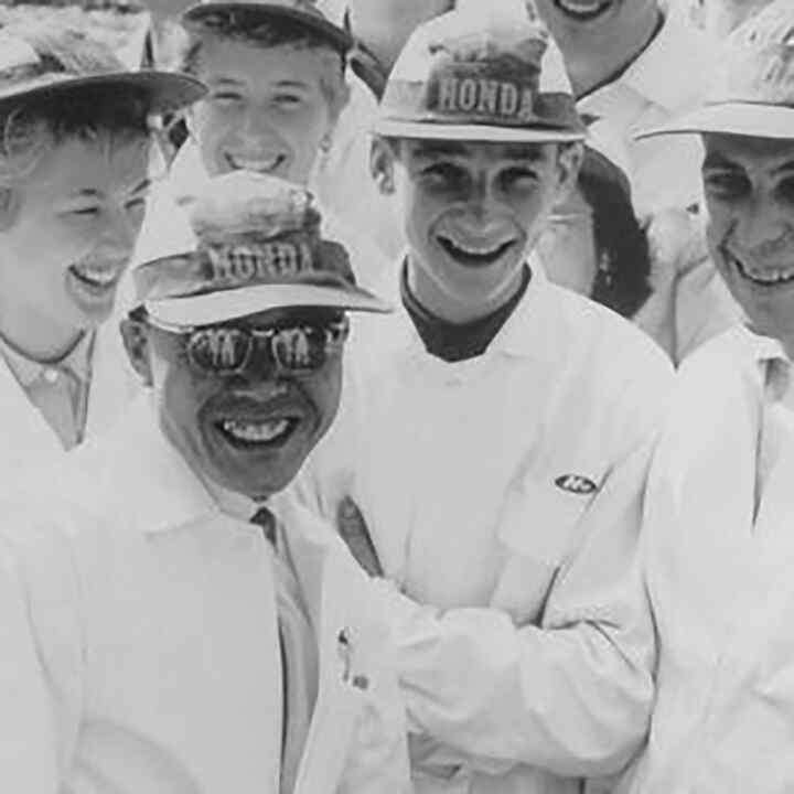 Soichiro Honda and some factory workers in white overalls.
