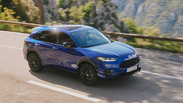 Honda ZR-V Hybrid SUV blue car driving on the road in a mountain location.