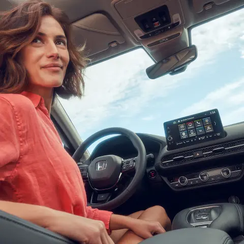 Female sitting if drivers seat using the Honda ZR-V hybrid infortainment screen.