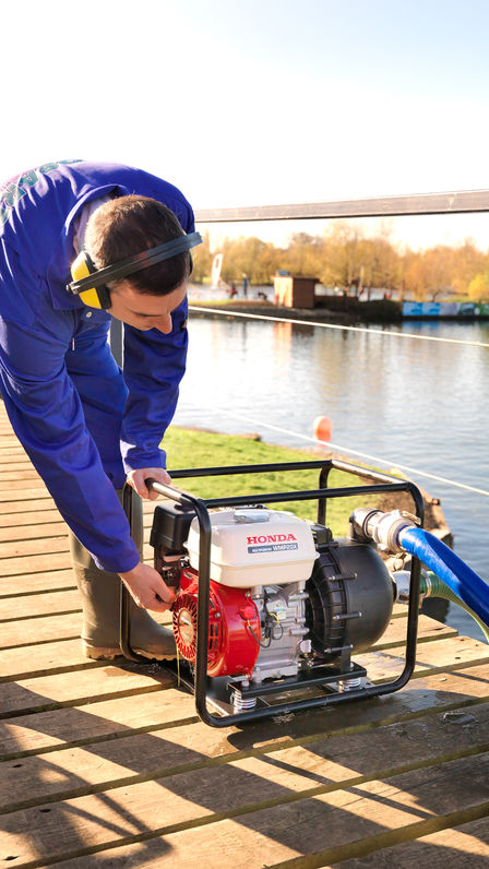 Close up of high flow rate/chemical water pump being used by a man in blue overalls