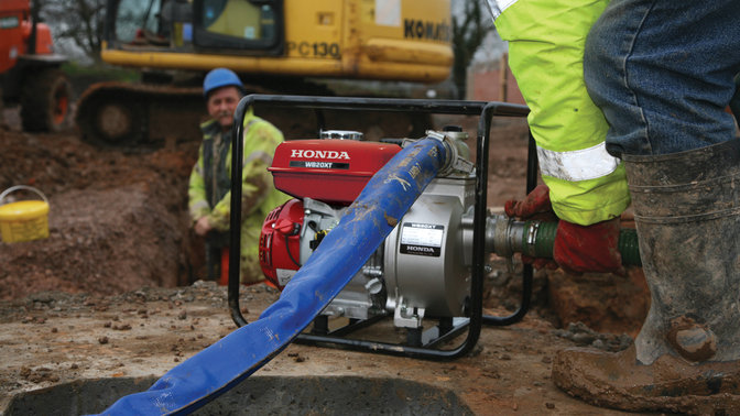 Close up of high flow rate water pump being used by worker on a building site.