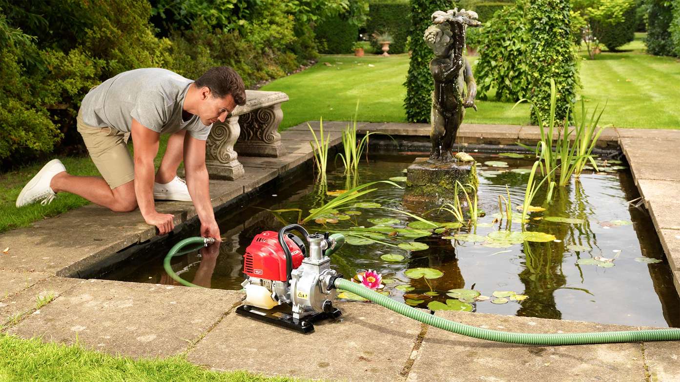 Lightweight water pump being used by a man in a pond.