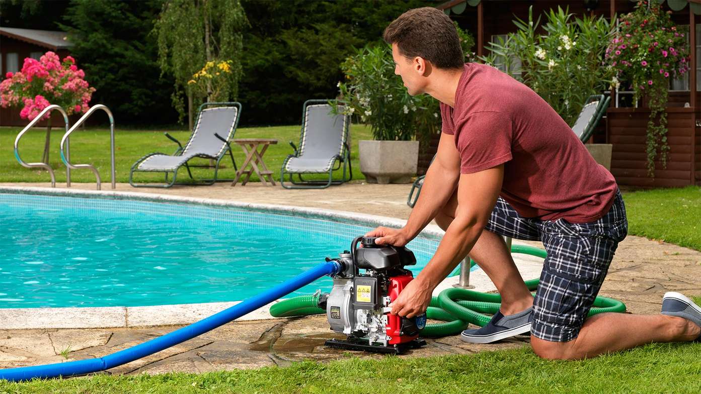Lightweight WX range Honda Water Pump being used by a man near a swimming pool. 