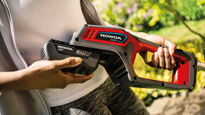 Man fixing battery on cordless trimmer