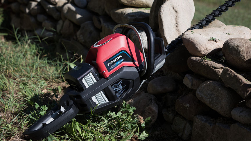 side view of honda cordless hedge trimmer laid down on a lawn